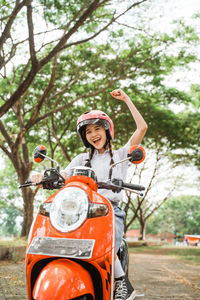 Side view of woman riding motor scooter on road