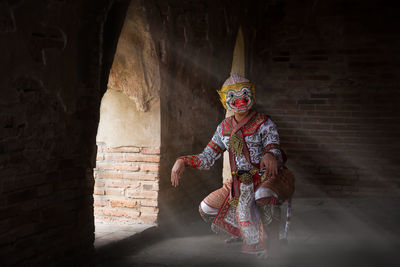 Man wearing costume while sitting in darkroom