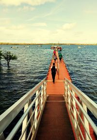 People on pier over sea against sky