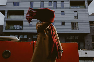 Woman standing by red building