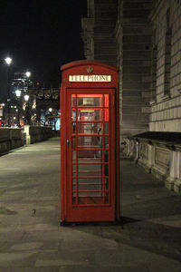 Red telephone booth at night