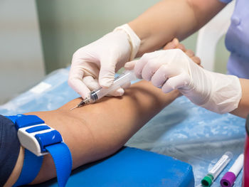 Cropped image of doctor injecting syringe to patient