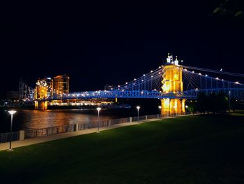 Illuminated bridge over river against sky at night