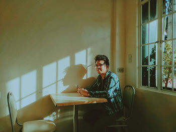 Young man sitting on table at home