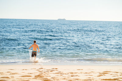 Shirtless man enjoying in sea against sky