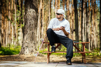 Full length of man sitting on tree trunk