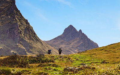 Rear view of hikers walking towards mountain against sky