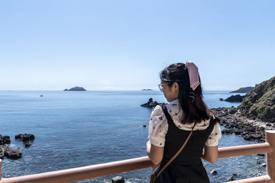 Side view of woman looking at sea against clear sky