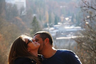 Affectionate couple standing against trees in city