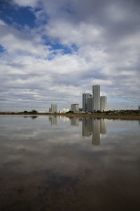 Buildings by river against sky in city