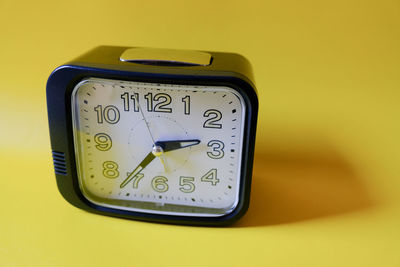 Close-up of clock on yellow wall