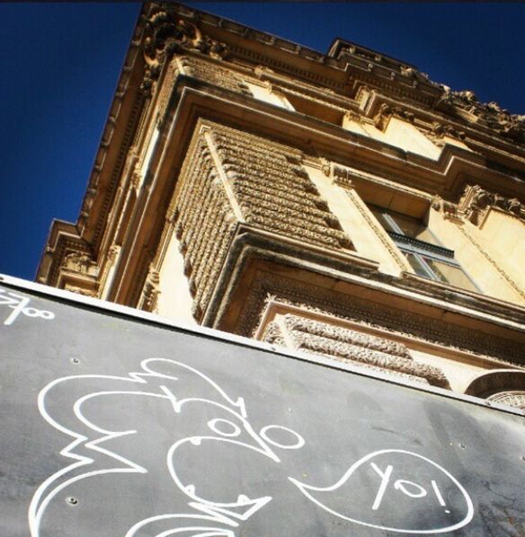 low angle view, architecture, text, building exterior, built structure, western script, clear sky, communication, blue, capital letter, day, information, no people, sign, outdoors, non-western script, human representation, building, sunlight, art and craft