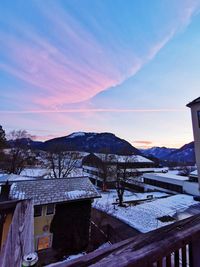 Snow covered houses against sky during sunset