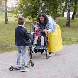 Family with child that has cerebral palsy, wheelchair user walking outdoors. integration