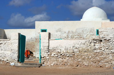 People on wall of building against sky