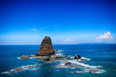 Rock formation in sea against blue sky