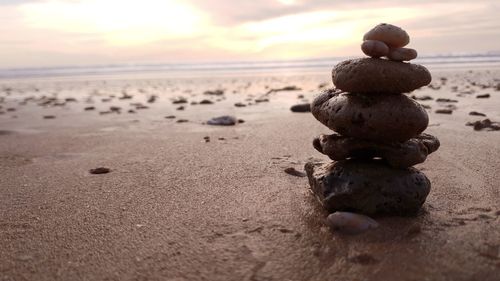 Close-up of stone stack on sand at beach against sky