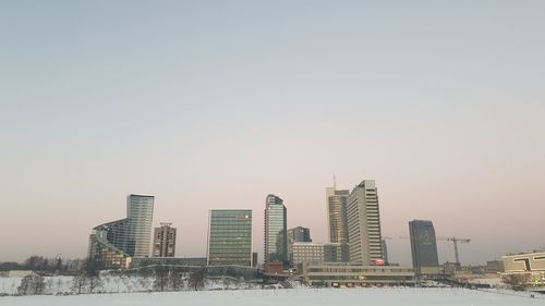 Modern buildings in city against clear sky during sunset