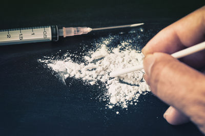 Cropped hand holding straw on cocaine