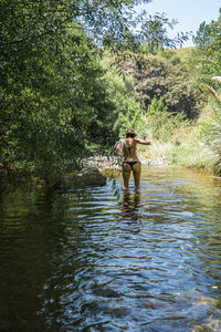 Man standing on riverbank in forest