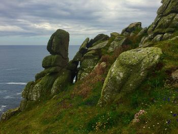 Scenic view of sea by cliff against sky