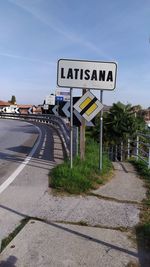 Road sign on street in city against sky