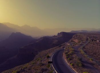 Road leading towards mountains against clear sky