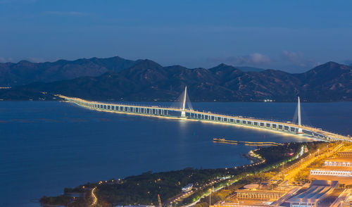 Illuminated bridge over river in city against sky