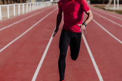 Rear view of man running on red umbrella