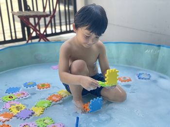 Boy playing with toy sitting in water