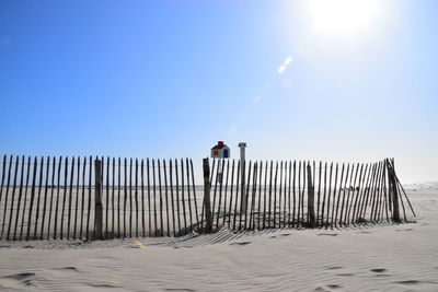 Rear view of a fence on beach against clear sky