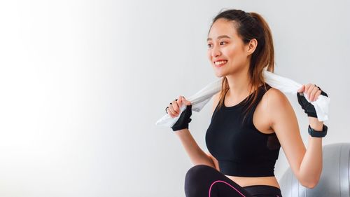 Young woman smiling while sitting against white background