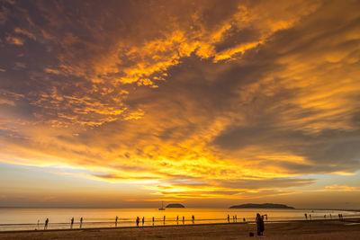 Scenic view of beach against dramatic sky during sunset