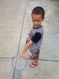 High angle view of cute boy playing badminton on road