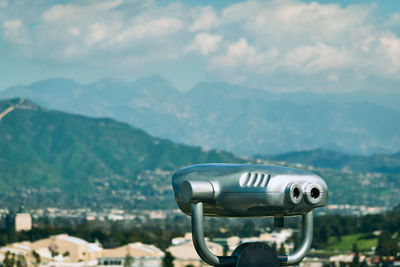 View of cityscape against mountain range with binocular