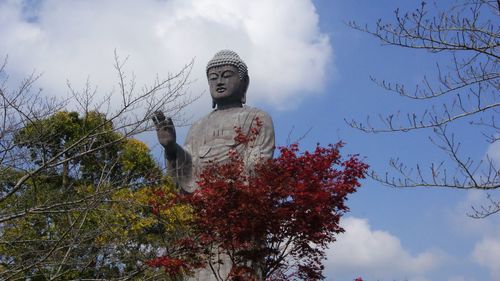 Low angle view of statue against trees against sky