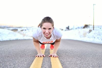 Portrait of young woman doing push-ups on street