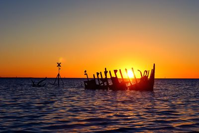 Silhouette ship in sea against sky during sunset