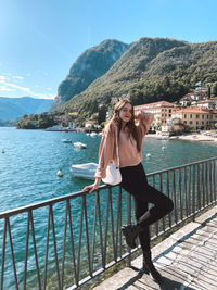 Full length of young woman standing by railing against mountain