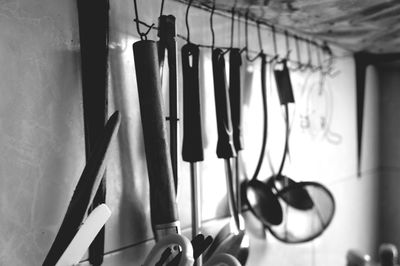 Various spoons hanging on hooks against wall in kitchen