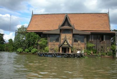House by lake against sky