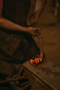 Low section of person holding cigarette on wood