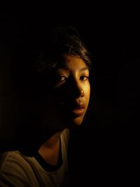 Close-up portrait of young man against black background