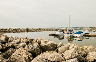 Sailboats moored in sea against sky