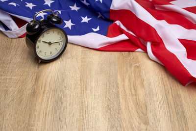 Alarm clock and american flag on wooden table