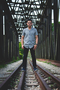 Portrait of young man standing on railroad track