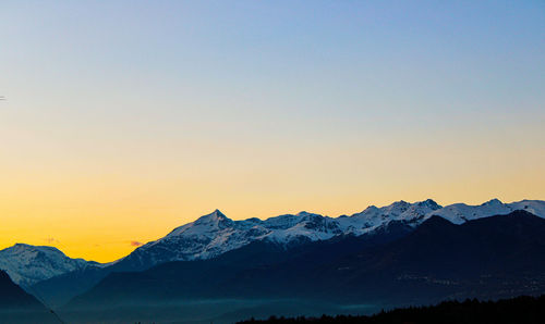 Scenic view of snowcapped mountains against clear sky during sunset