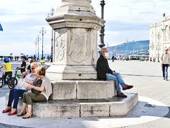 People sitting on staircase of historical building