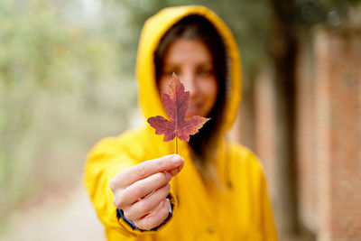 Woman holding autumn leaf in forest