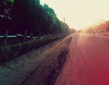 Empty road amidst trees against clear sky